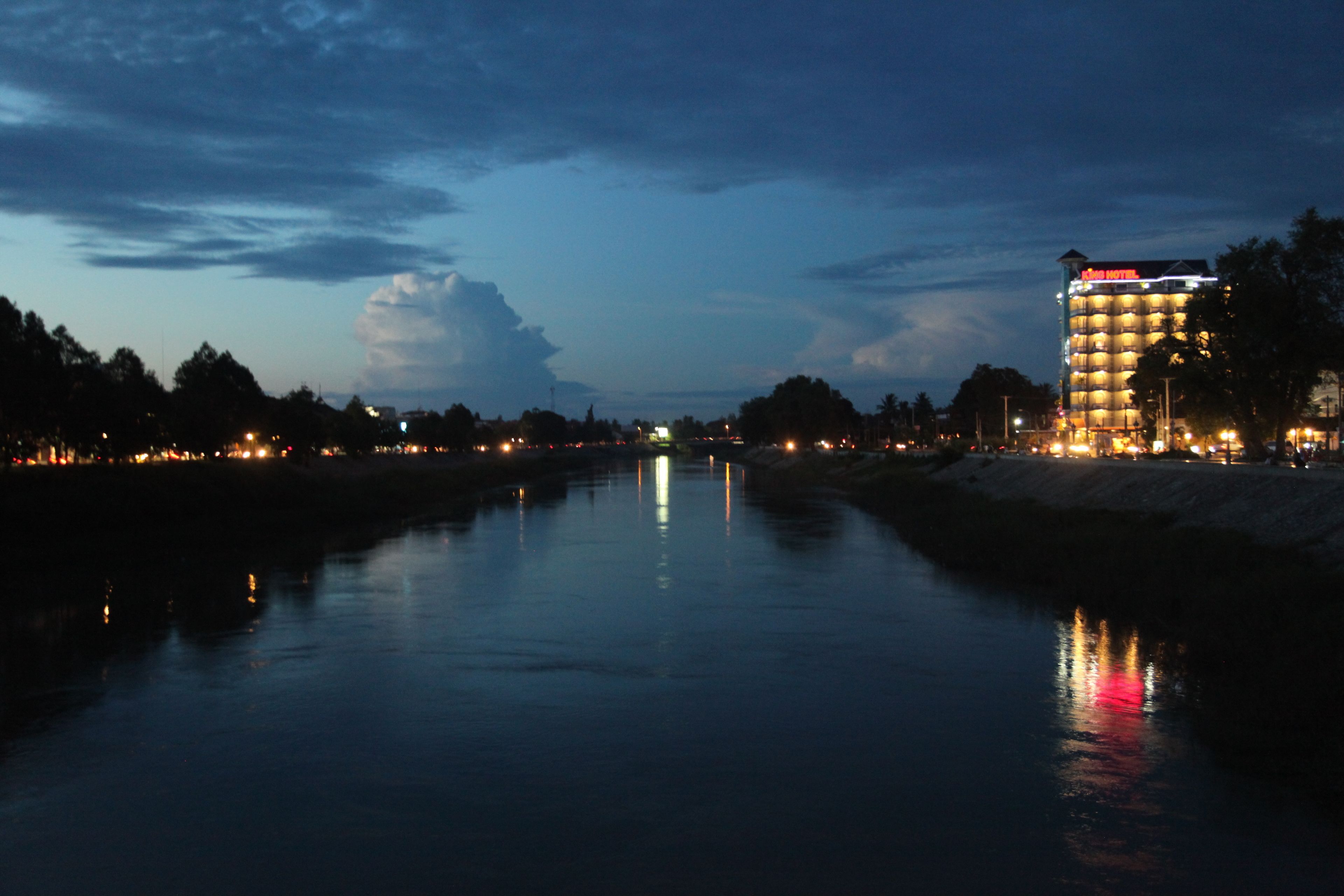 A hotel by a calm river at dusk.
