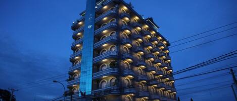 A multi-story hotel with balconies, a central tower, and a sign indicating a restaurant.