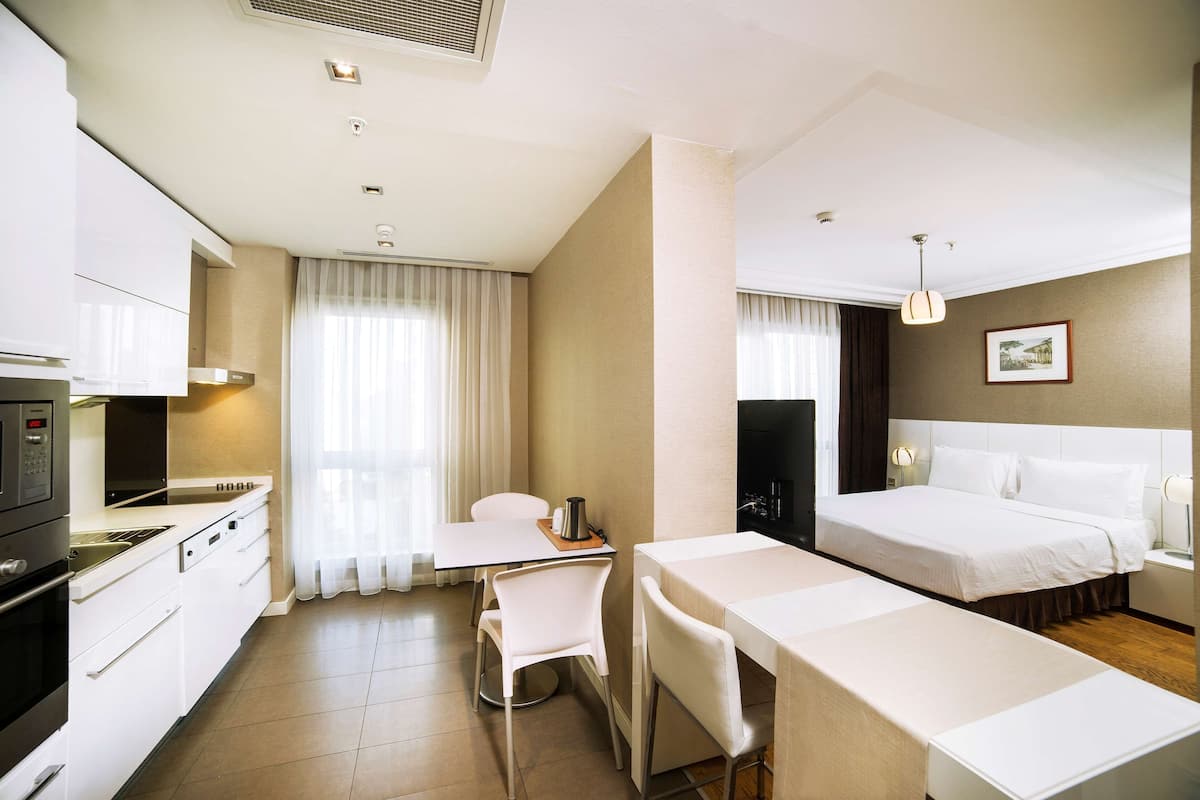 Ein Hotelzimmer mit Küchenzeile, einem Bett, einem Esstisch und einem Stuhl.
