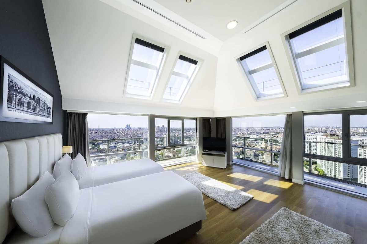 Ein modernes Schlafzimmer mit Stadtblick, großen Fenstern und einem Flachbildfernseher.