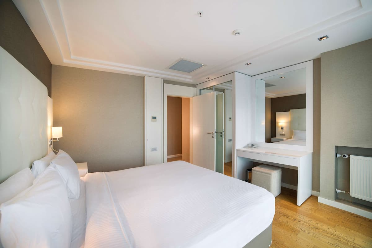Ein Hotelzimmer mit Bett, Schreibtisch, Spiegel und begehbarem Kleiderschrank.