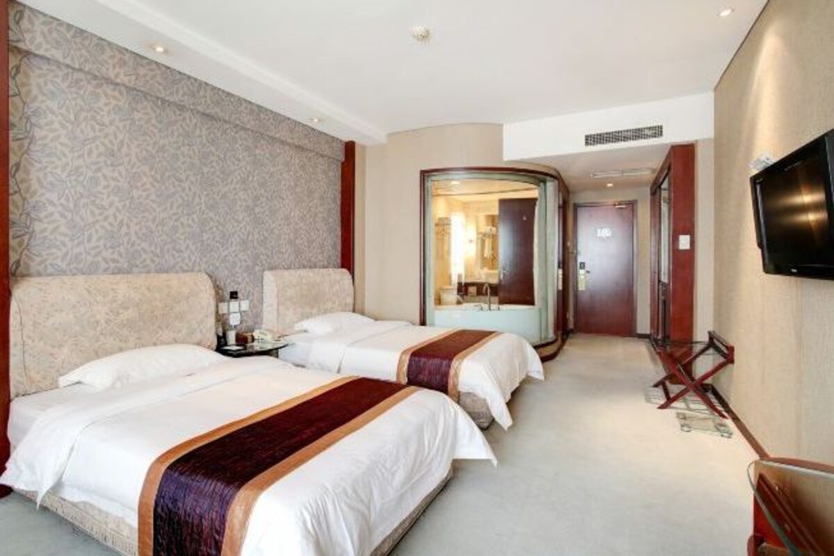Ein Hotelzimmer mit zwei Betten, einem Fernseher und einem Glaskastenbad.