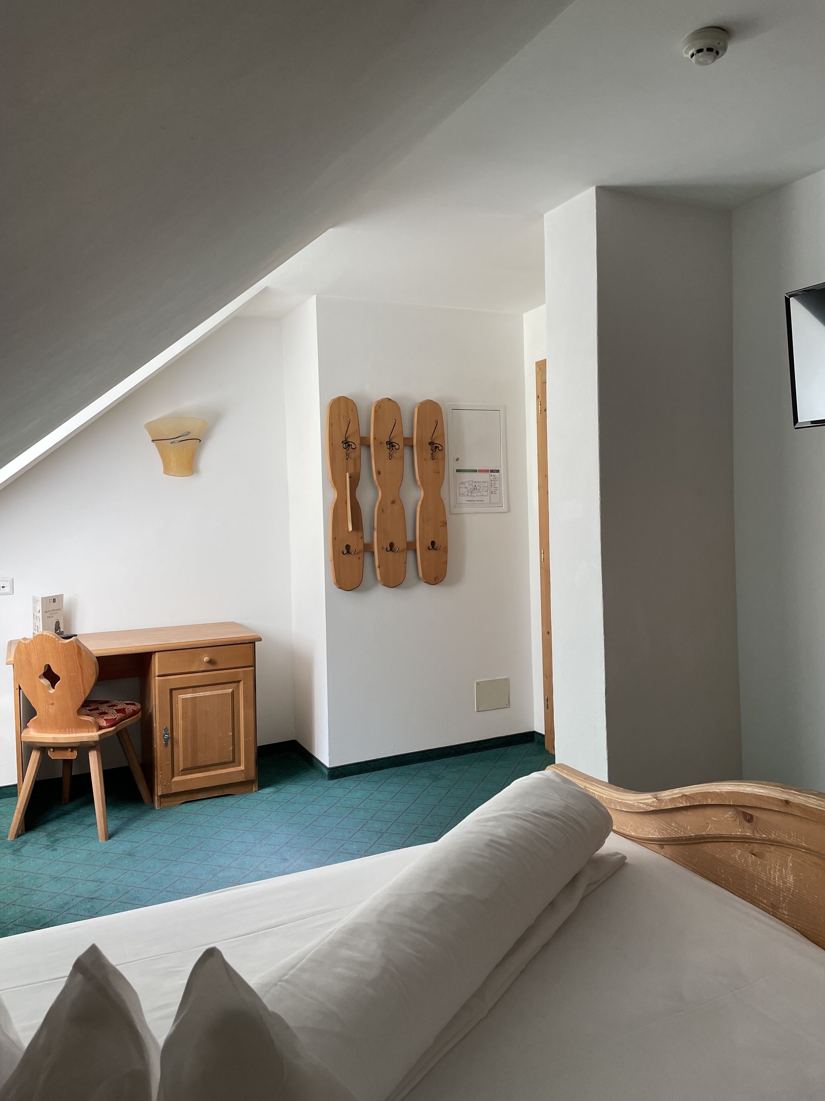 Un dormitorio con una cama, un escritorio y una silla. Hay esquíes colgados en la pared.