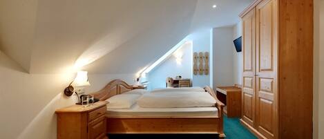 A bedroom with a wooden bed, a nightstand, a dresser, and a wardrobe.