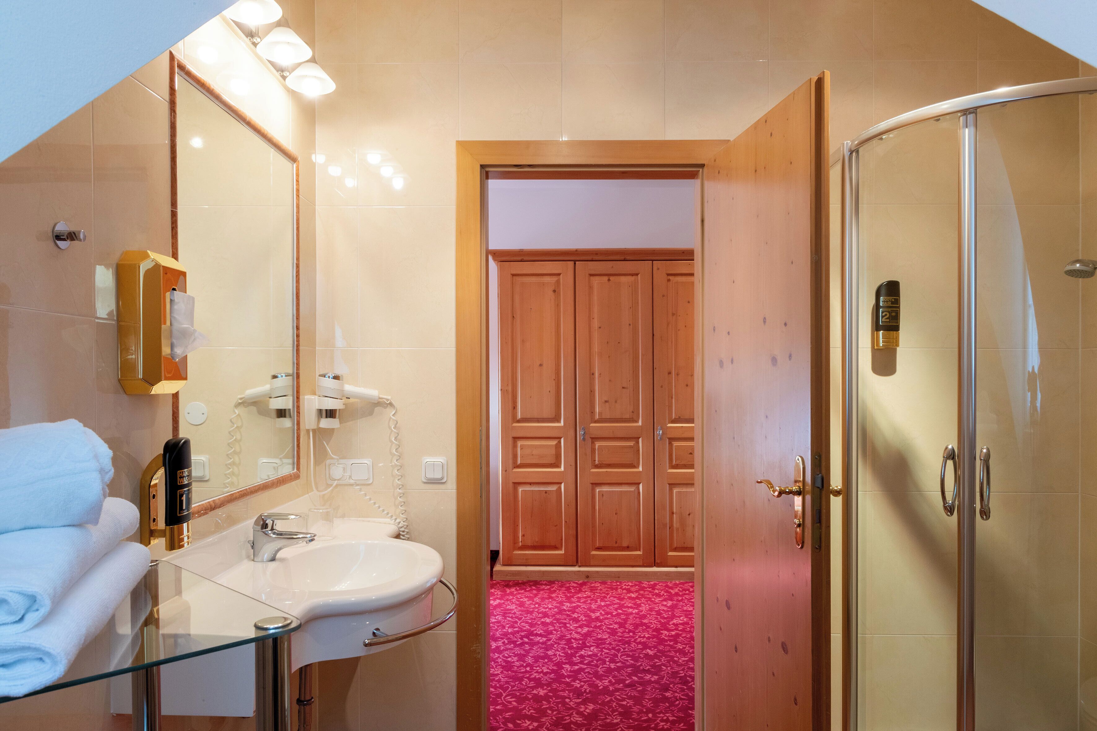 Ein Badezimmer mit einem Glaswaschbecken, einem Spiegel, einem Handtuchhalter und einer Duschkabine.