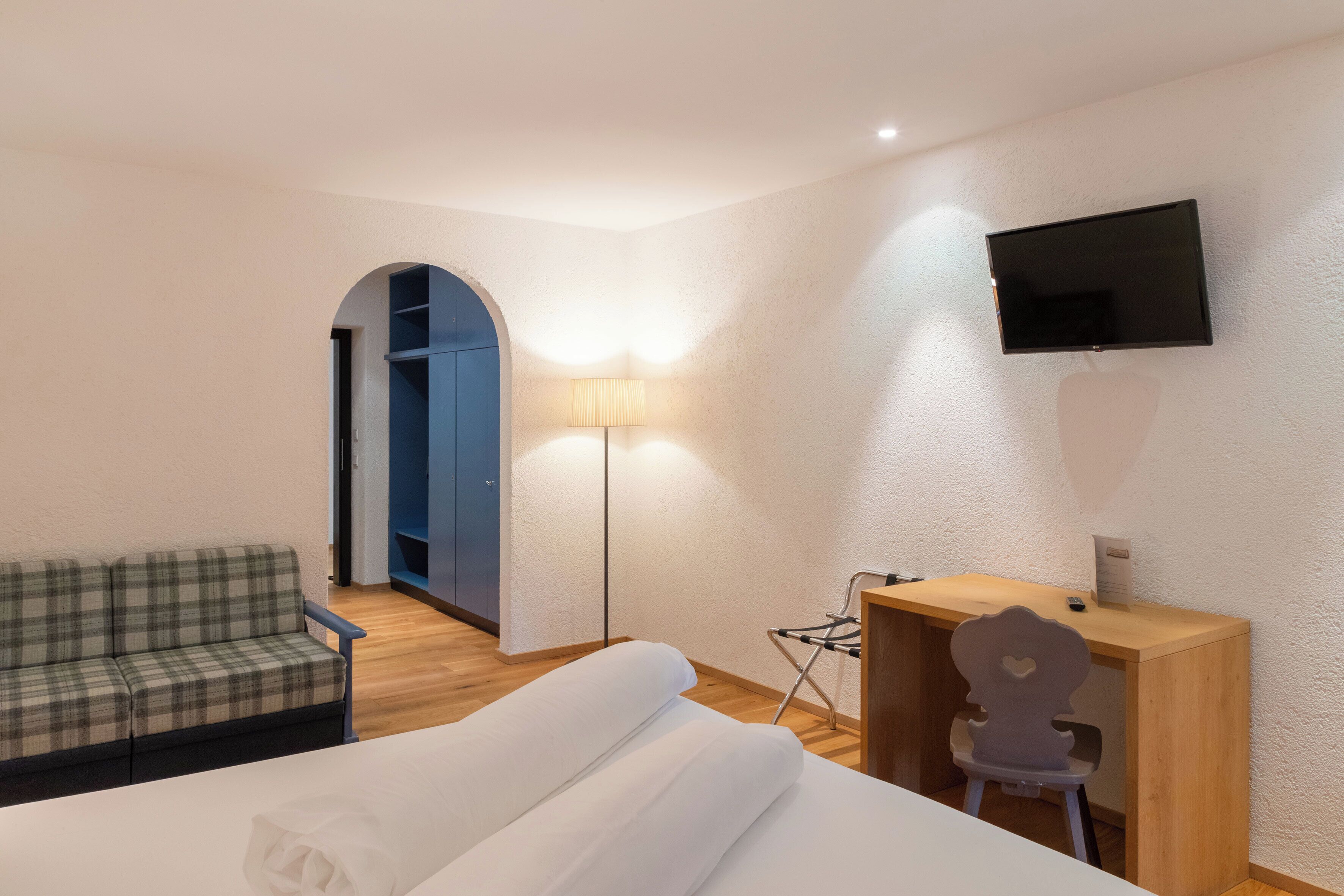 Une chambre d’hôtel équipée d’un lit, d’un bureau, d’une chaise, d’une télévision et d’une lampe.