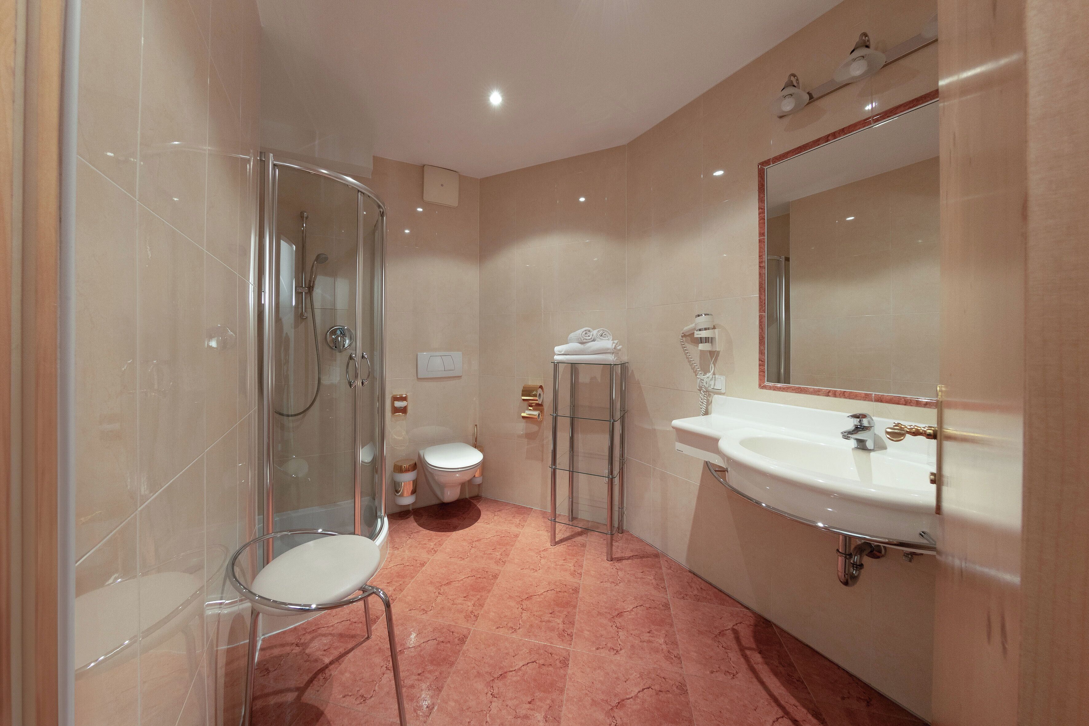 A bathroom with a glass shower enclosure, a toilet, a sink with a mirror, and a towel rack.