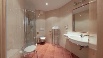 Une salle de bain avec une douche à parois de verre, des toilettes, un lavabo avec un miroir et un porte-serviettes.