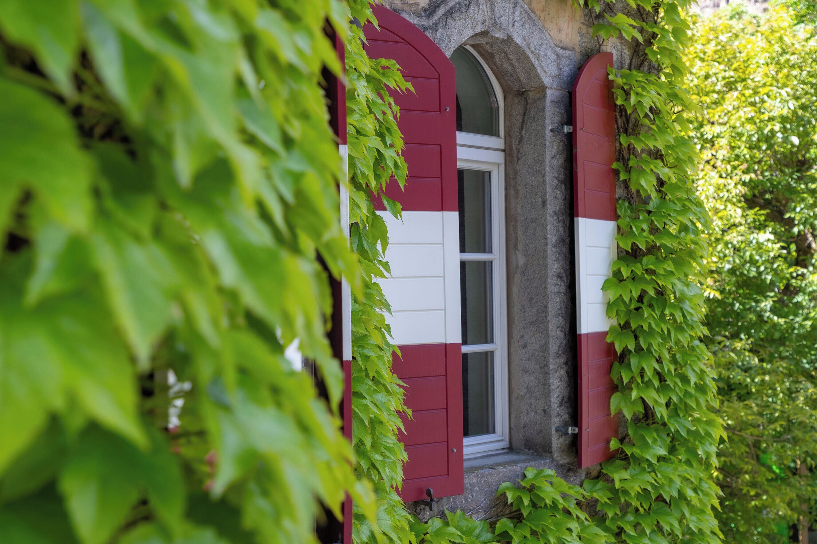 Un bâtiment à la façade rouge et blanche, en partie recouverte de lierre vert.