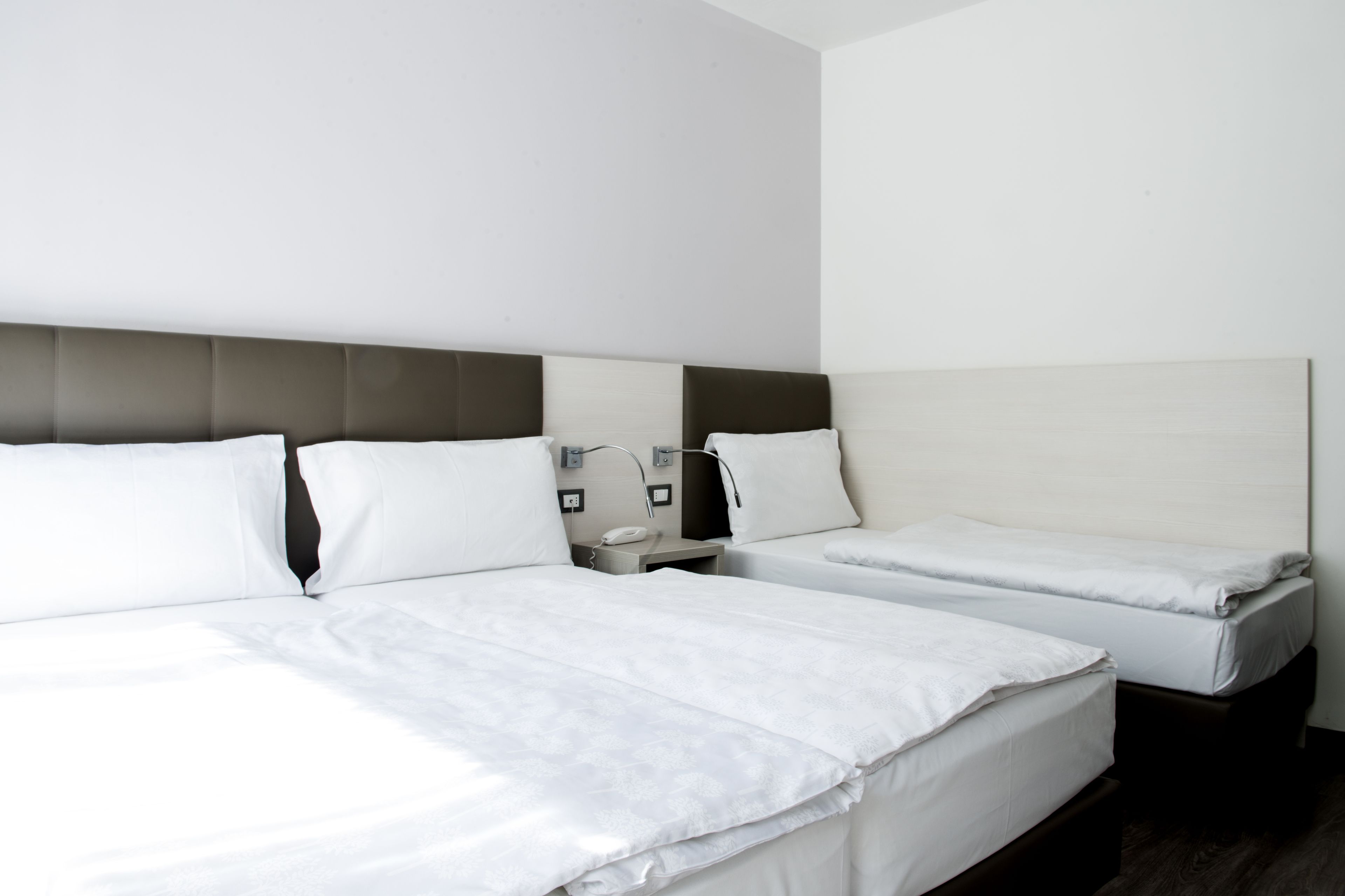 A hotel room with two beds, each with a headboard and bedside tables.