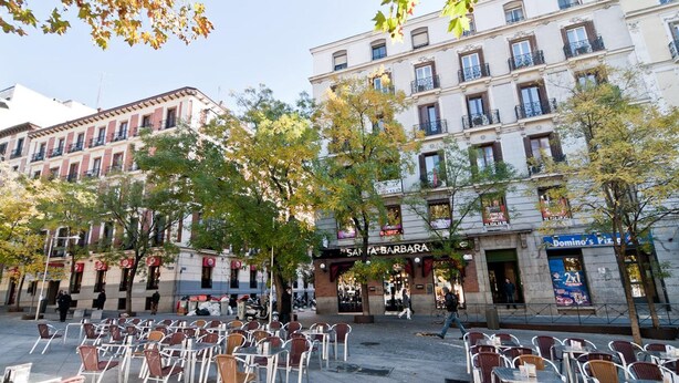 A street with outdoor seating, a building with a 'Santa Barbara' sign, and a 'Domino's Pizza' storefront. - Hostal Asuncion (Madrid)
