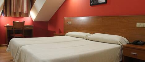 Habitación de hotel con dos camas, un escritorio, una silla y un cuadro en la pared.
