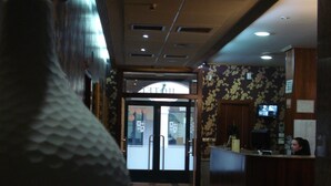 A hotel lobby with a reception desk, a large vase, and a door leading to the hotel rooms. - El Castillo (Ponferrada)