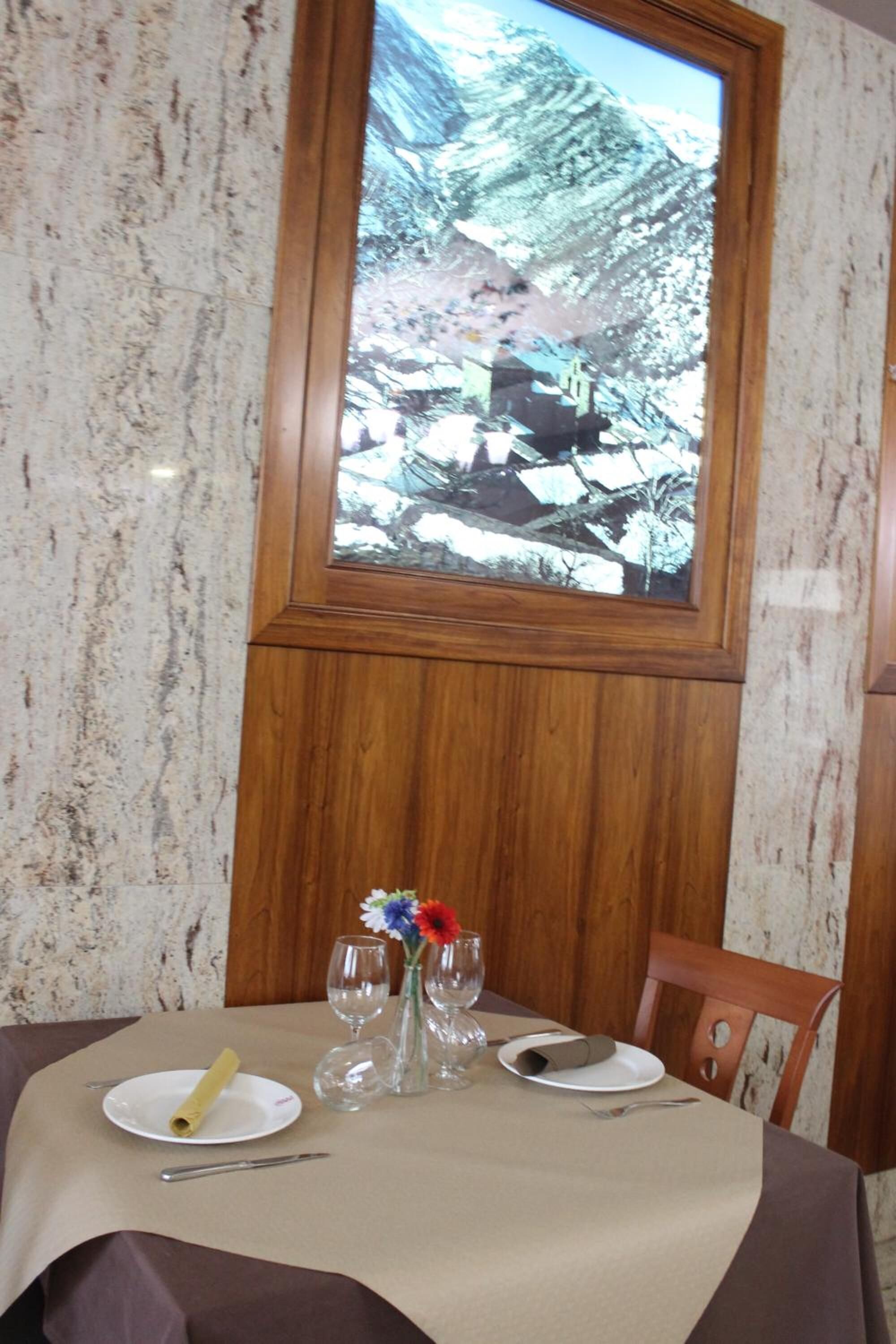A dining table set with a plate, a rolled napkin, wine glasses, and cutlery.