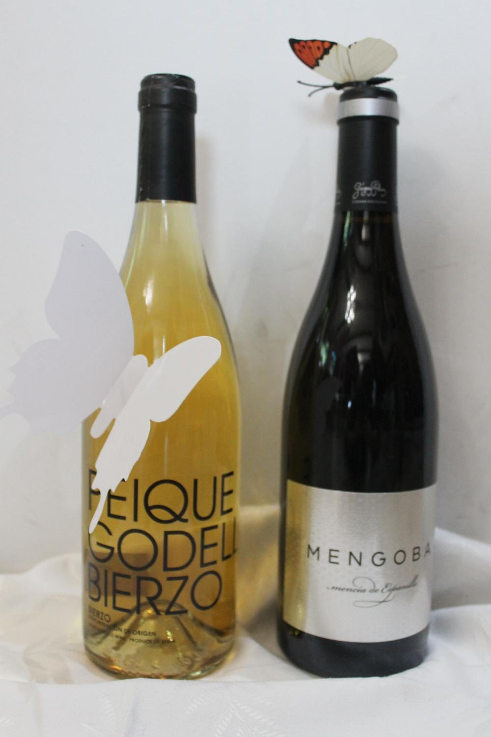 To vinflasker, hvoraf den ene er mærket 'PEQUE GODELL BIERZO' og den anden 'MENGOBAR'.