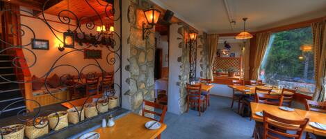 A restaurant with stone walls, wooden furniture, and a view of greenery outside.