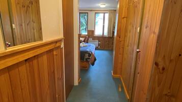 Un pasillo estrecho con paredes de madera y una alfombra azul que conduce a un dormitorio con cama y ventana.