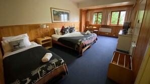 A hotel room with two beds, a desk, a chair, a television, and a window with curtains.