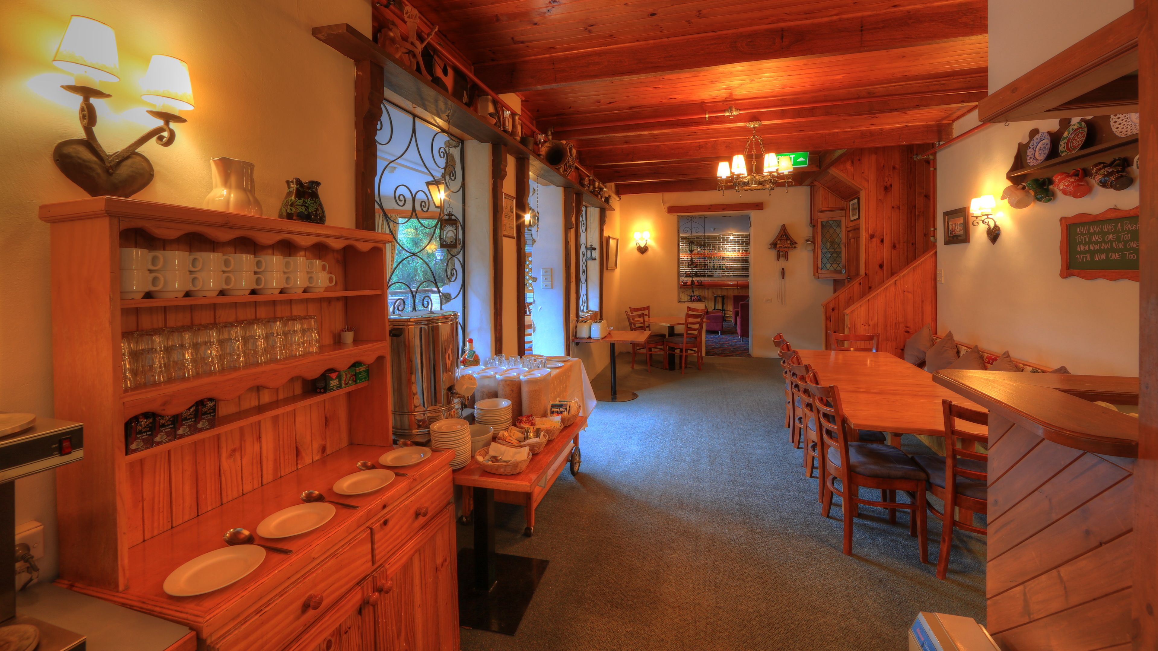 Een gezellig restaurant met houten inrichting, een buffet en een eethoek met tafels en stoelen.
