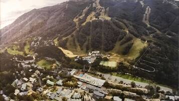 A mountainous landscape with a residential area at the base, featuring houses and a swimming pool.