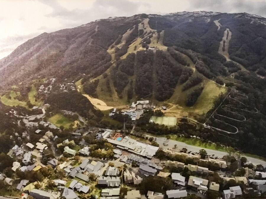 A mountainous landscape with a residential area at the base, featuring houses and a swimming pool.