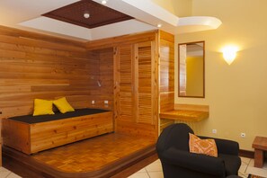 A room with a wooden bed, a black sofa, and a wooden wardrobe. - Aldeia da Fonte Hotel (Lajes do Pico)