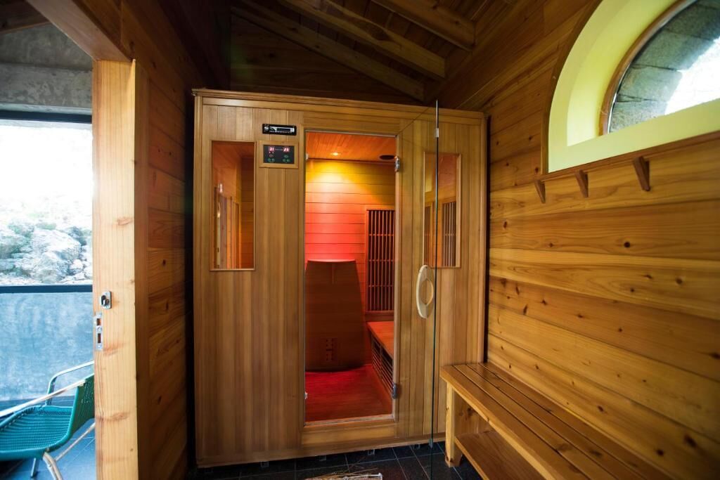 Un sauna en bois doté d’une porte en verre, d’un panneau de commande et d’un banc.