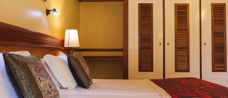 Ein Hotelzimmer mit Bett, Kissen, Lampe und Kleiderschrank.