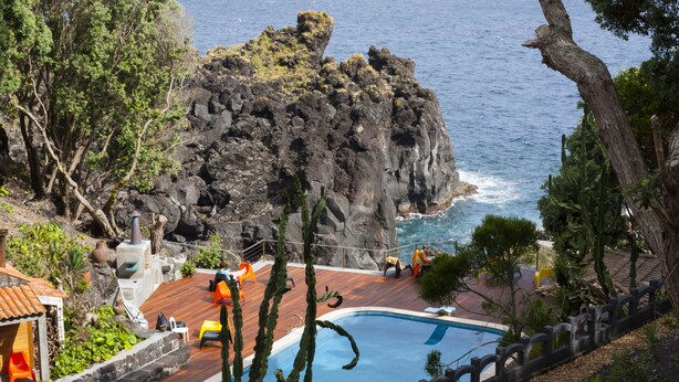 A pool area with a view of the ocean and rocky cliffs.