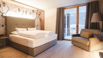 A hotel room with a large bed, a sofa, a desk, and a view of the outdoors.