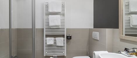 Un baño moderno con cabina de ducha de vidrio, lavamanos blanco, inodoro y bañera.
