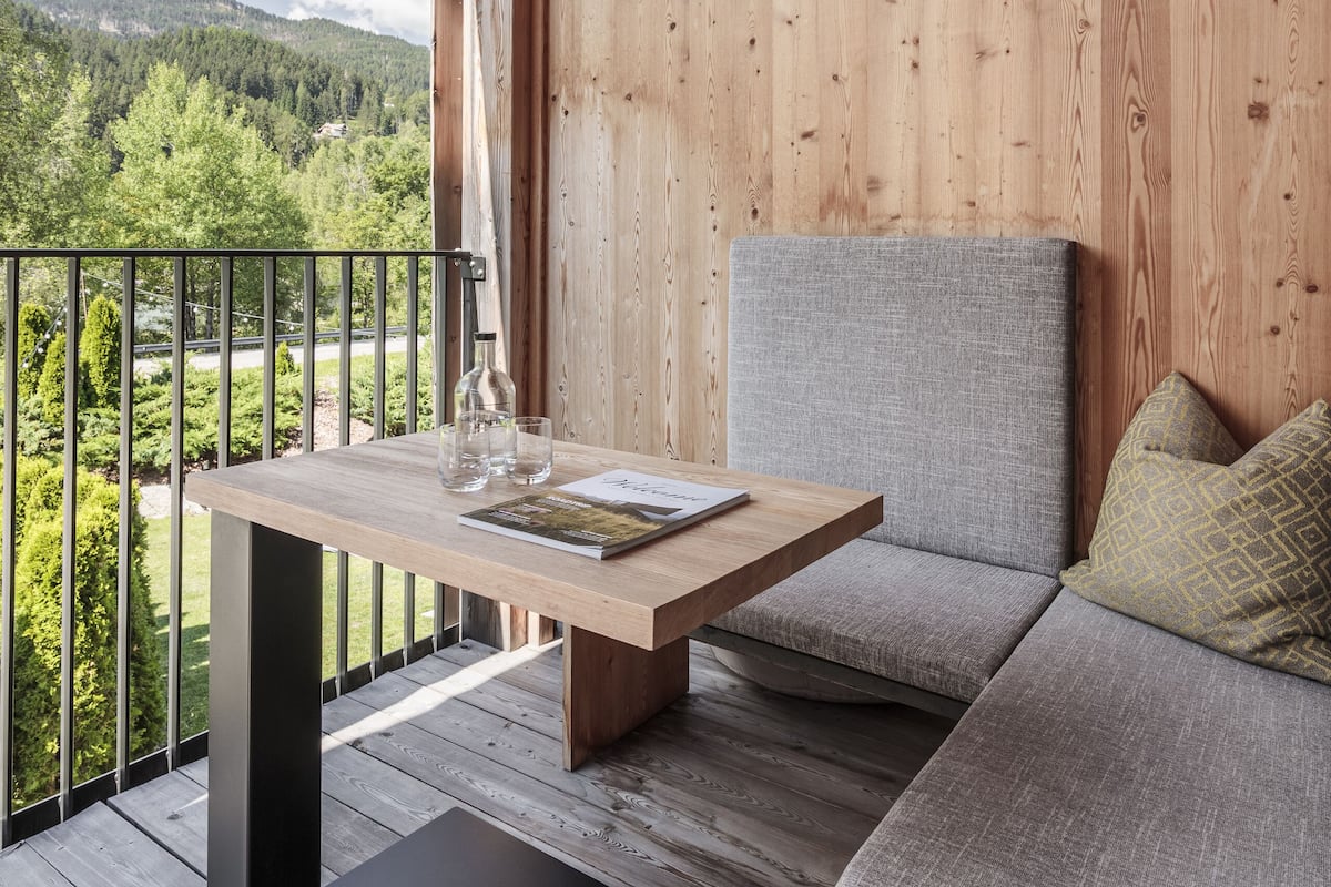 A wooden deck with a table and seating area, overlooking a mountainous landscape.