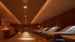 A spa area with wooden paneling, a reception desk, and multiple sun loungers aligned along a central walkway. - Christof Hotel (Monguelfo)