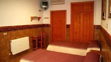 A room with two beds, a chair, a radiator, and a television.