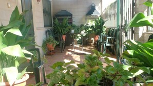 A patio area with potted plants, a grill, and outdoor furniture.