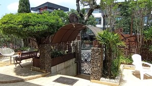 A gated entrance with a metal archway, a bench, and a small table with chairs. - Hotel Don Alfonso (Pereira)