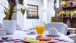 A breakfast setting with a table, plates of food, a glass of orange juice, and a potted plant. - Hotel Don Alfonso (Pereira)