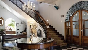 A grand staircase with ornate railings, a chandelier, and a checkered floor. - Hotel Don Alfonso (Pereira)