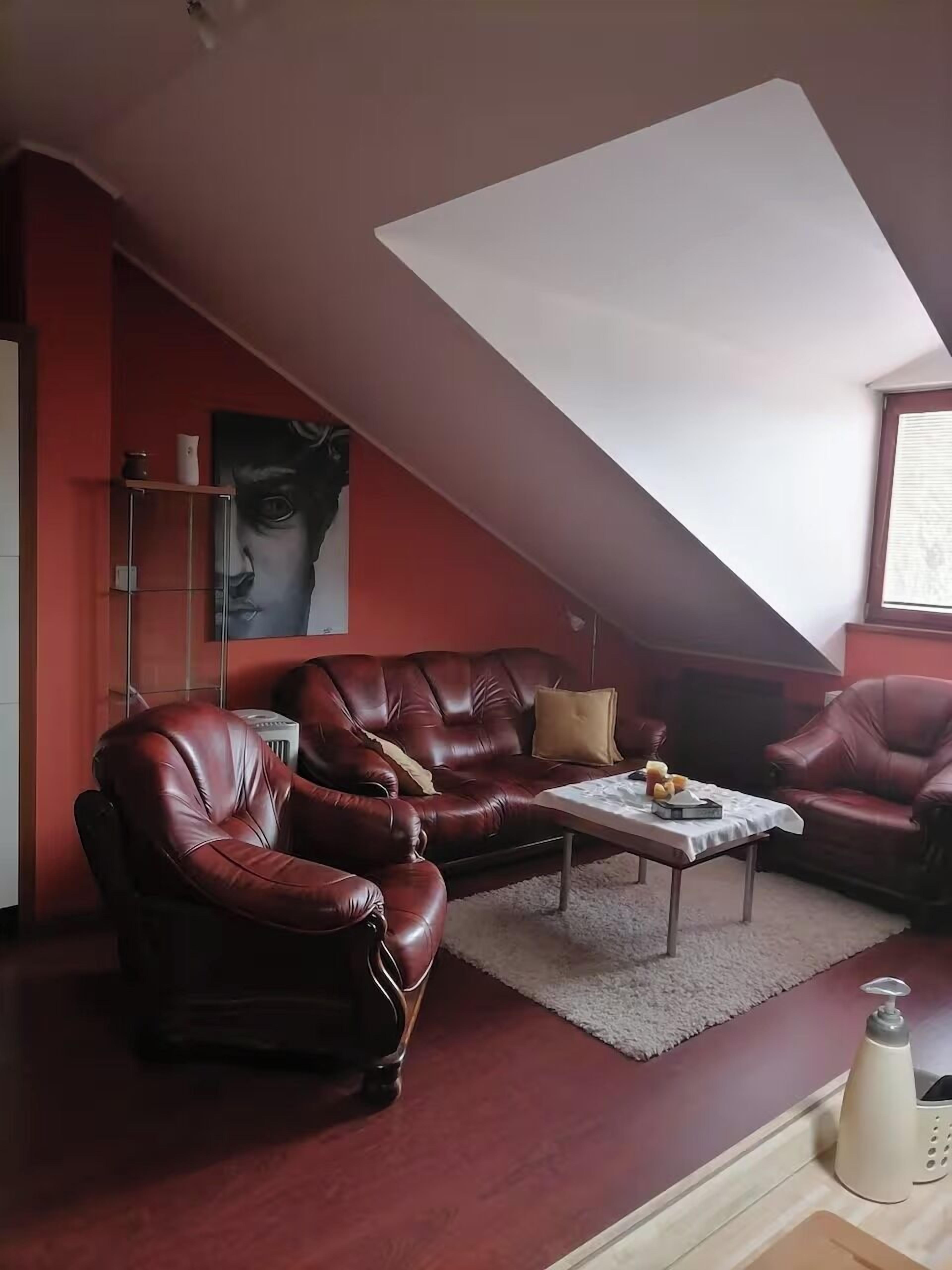 Una sala de estar con un sofá de cuero rojo, una mesa de centro y un cuadro en la pared.