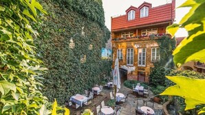 A courtyard with outdoor seating and a building covered in ivy.