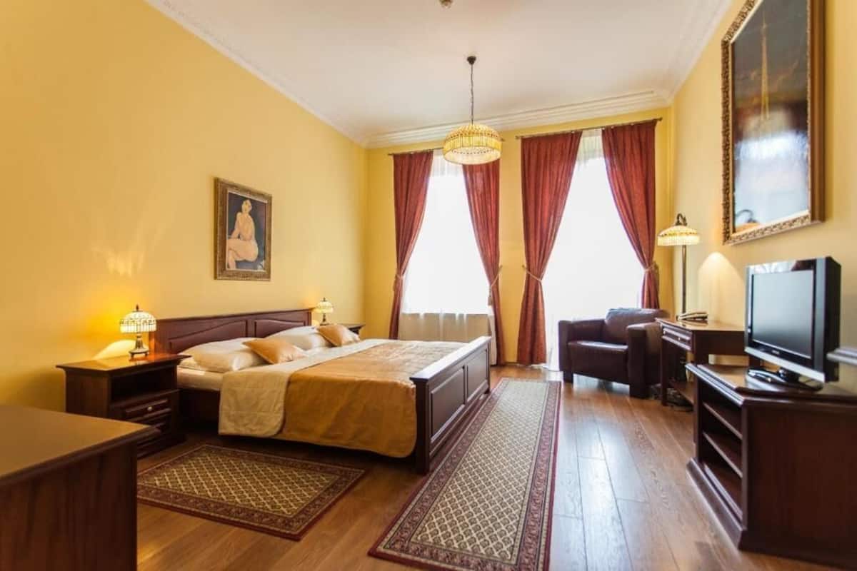 Een hotelkamer met een groot bed, een bureau, een stoel, een televisie en een raam met gordijnen.