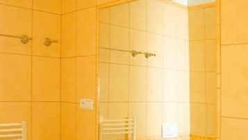 A bathroom with yellow tiled walls, a white sink, a mirror, and a towel rack.