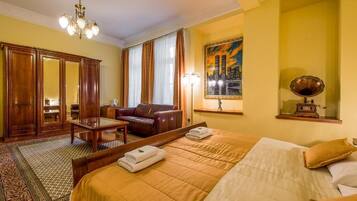 Ein Hotelzimmer mit einem großen Bett, einem Holzschrank, einem Ledersofa, einem Schreibtisch und einem Stadtbild.