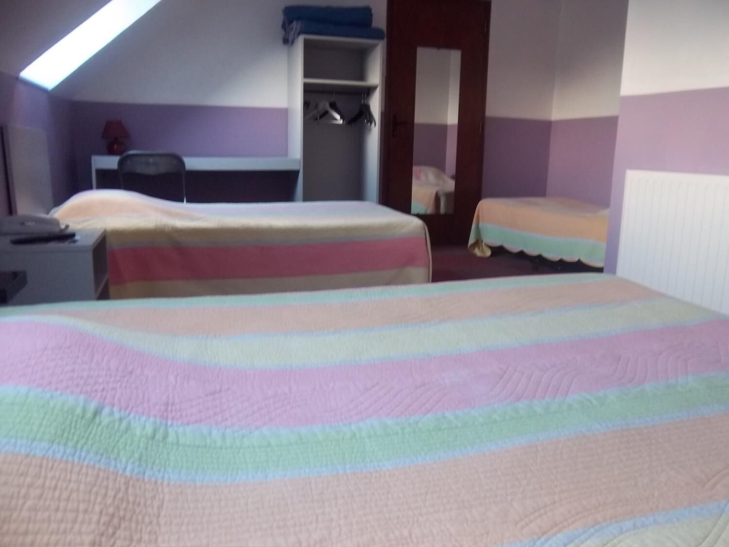Un dormitorio con dos camas, un escritorio y un armario.