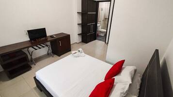 Une chambre d’hôtel avec un lit, un bureau équipé d’un ordinateur, une armoire et une salle de bain visible à travers une porte ouverte.