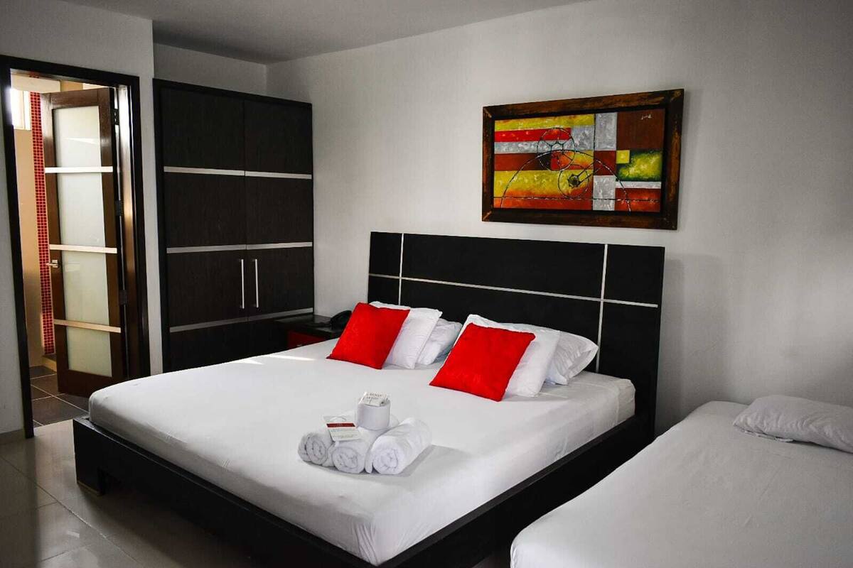Une chambre d’hôtel moderne avec un grand lit, une table de chevet, une armoire et un tableau au mur.