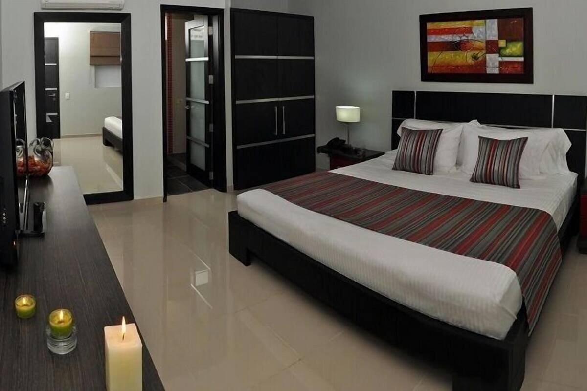 Une chambre d’hôtel moderne avec un grand lit, des tables de chevet, une armoire et un tableau au mur.