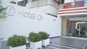 Entrada de hotel con un cartel que dice "Hotel or" y plantas en macetas al frente.