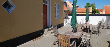 An outdoor patio with wooden furniture and a white fence.