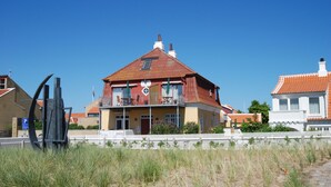 Een huis met twee verdiepingen, een rood dak, een balkon en een witte hekken voor.
